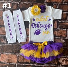 This Purple and Yellow Vikings set is just an example of the sports outfit designs we have available. Our Sports Collection Designs are unique to our company, and we are currently growing in the number of teams we cover. If you would like a specific team feel free to message me and we can make unique designs for your team. All of our sports outfits are sold as a set with bodysuit, matching chiffon bloomers or tutu, personalized leggings, and coordinating color headbands.  Each bodysuit/shirt is handmade after your order is placed. Your items will be immediately shipped after completion and you will receive a tracking number and notification as soon as the item is shipped. Machine wash all designs inside out in cold water, and tumble dry LOW, or hang to dry. Do not iron or bleach directly o White Cotton Sports Sets, White Cotton Sets For Sports Events, White Letter Print Sets For Playtime, White Cotton Cheerleading Sets, White Sets With Letter Print For Birthday, Customizable White Sets For Birthday, Girls Football Outfit, Viking Baby, Girls Football