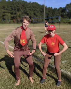 two people in costume standing on a field with one person wearing a tie and the other holding his hands behind his back