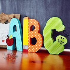 the letters are made out of wood and have different designs on them, including an apple