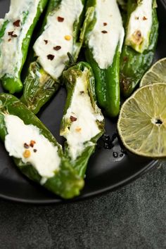 a plate with some green peppers covered in cheese and a lemon wedge next to it