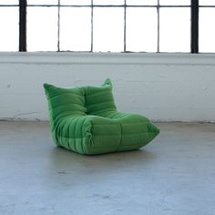 a green bean bag chair sitting in an empty room