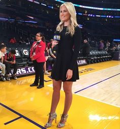 a woman standing on top of a basketball court wearing high heeled shoes and holding a microphone