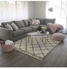 a living room with grey couches and white rugs on top of the floor