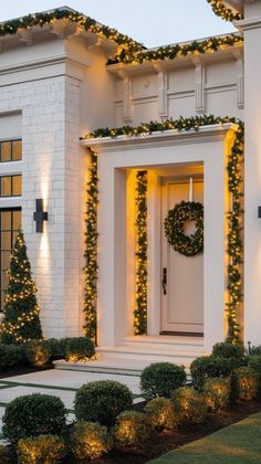 a white house decorated with christmas lights and wreaths