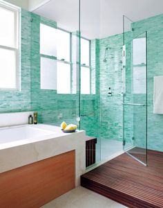 a modern bathroom with green tiles and wood flooring, along with a walk in shower