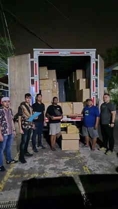 group of people standing in front of a moving truck with boxes on the back door