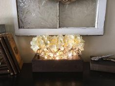 a vase filled with white flowers sitting on top of a table next to two books