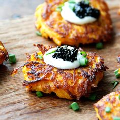 crab cakes with black cavia and green onions on a wooden cutting board, ready to be eaten