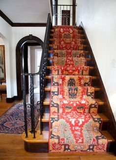 a stair case with rugs on the bottom and handrail