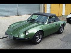 a green sports car parked in front of a garage