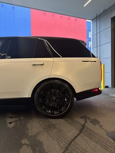 a white range rover parked in front of a multi - colored building with black rims