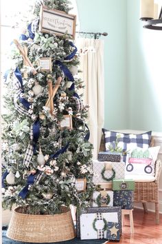 a christmas tree decorated with blue and white ribbon, ornaments and other holiday decorations in a living room