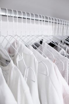 white shirts hanging on clothes racks in a closet