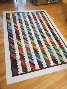 a multicolored quilt sitting on top of a hard wood floor