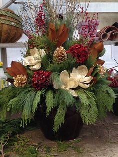 a vase filled with lots of different types of flowers and greenery on top of a table