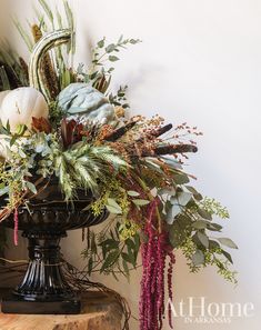 a vase filled with lots of flowers on top of a wooden table next to a mirror