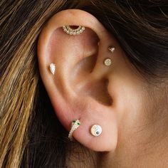 a woman's ear with three different piercings on her left side, and two smaller ones in the middle