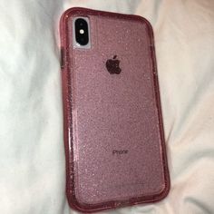 an iphone case sitting on top of a white bed covered in pink glitters,