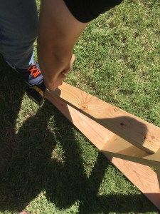 a person cutting wood with a pair of scissors on top of the wooden planks