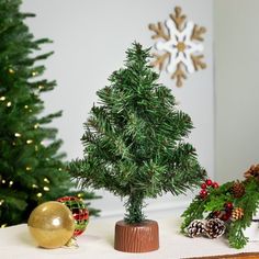 a small christmas tree sitting on top of a table next to a gold ornament