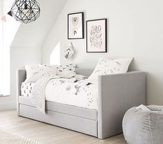 a bedroom with white walls and flooring has a gray daybed in the corner