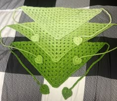 a green crocheted blanket on top of a black and white checkered bed spread