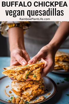 a person is stacking up food on a plate with the words spicy buffalo chicken vegan quesadillas