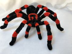 an orange and black spider sitting on top of a white surface