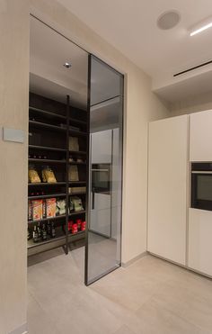 an empty room with glass doors and shelves full of food on the floor, in front of a white wall