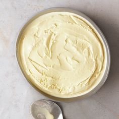 a bowl filled with yellow cake batter on top of a white countertop next to a knife