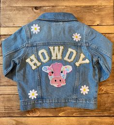 a denim jacket with embroidered cow on the back