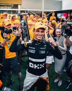 a man holding up a trophy while standing in front of a group of other people