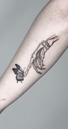 a black and white tattoo on the arm of a person holding hands with a butterfly