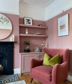 a living room with pink walls and a fireplace in the corner is furnished with furniture