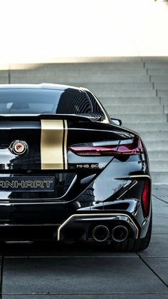 the rear end of a black sports car with gold stripes on it's side