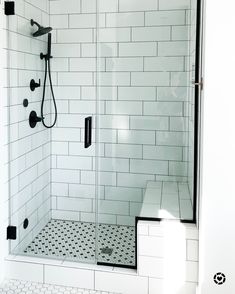 a white tiled shower with black and white floor tiles on the walls, along with a walk in shower