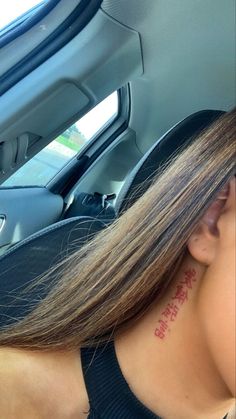 a woman with a tattoo on her neck sitting in a car