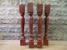 three red candlesticks sitting on top of a wooden table next to a brick wall