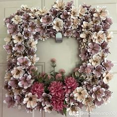 a wreath made out of paper flowers hanging on a door