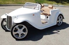 an old model white car parked in a parking lot