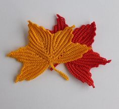 two crocheted autumn leaves laying on top of each other in red, yellow and orange