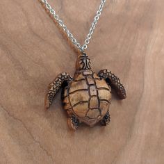 "This wood turtle pendant is carved from solid maple. Available in a natural (light) or antique (dark) finish. 18\" decorative stainless steel chain included. The item ordered comes in a cute gift bag. Wood measures 2\" tall x 2\" wide. Free shipping for US customers! Made and shipped from the United States. Interested in wholesale? No problem! Send me a message and I will be happy to work with you! Every piece of wood is naturally different, the grain in your jewelry may differ slightly from th Nickel-free Brown Necklace For Gift, Brown Necklaces With Lobster Clasp As Gift, Brown Necklace With Lobster Clasp As Gift, Brown Necklace With Lobster Clasp For Gift, Engraved Brown Necklace For Gift, Wood Necklace Pendant, Wood Turtle, Sea Turtle Necklace, Musician Gifts