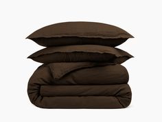 three pillows stacked on top of each other in front of a white background and the bottom one is dark brown