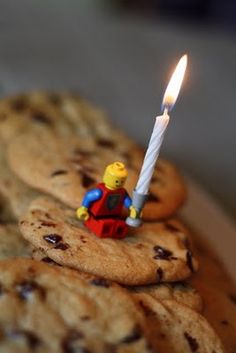 a lego man holding a lit candle on top of cookies