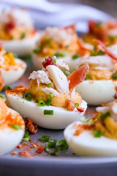 several deviled eggs with bacon and chives on a plate, ready to be eaten