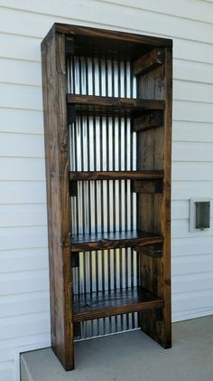 a wooden book shelf sitting on the side of a house