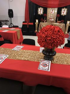 a red table topped with a vase filled with red flowers and gold sequins