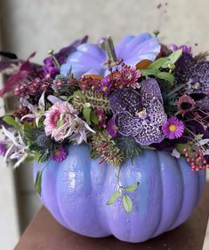 a purple pumpkin filled with lots of flowers