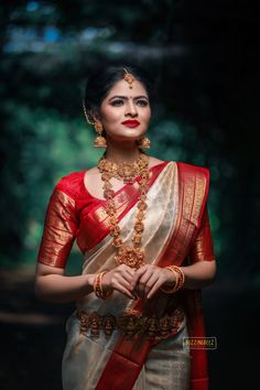 a woman in a red and white sari with gold jewelry on her neck, posing for