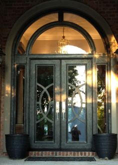 the front door to a building with two large planters